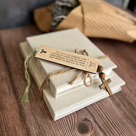 A collection of wooden bookmarks with Bible verses written on them, placed on a wooden surface with a burlap-wrapped object in the background.