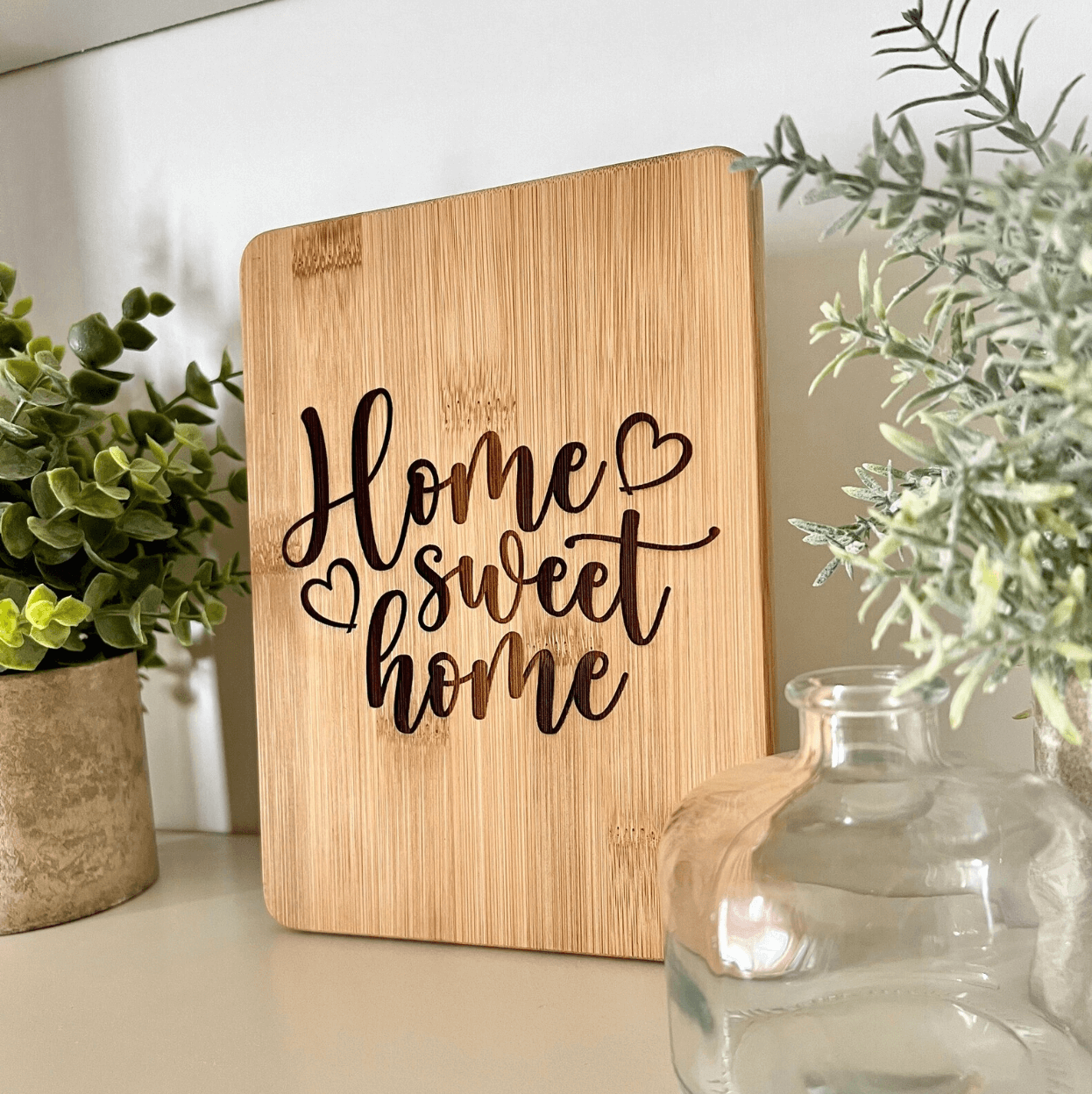 A bamboo charcuterie serving board with 'Home Sweet Home' text etched on it, placed on a kitchen counter.