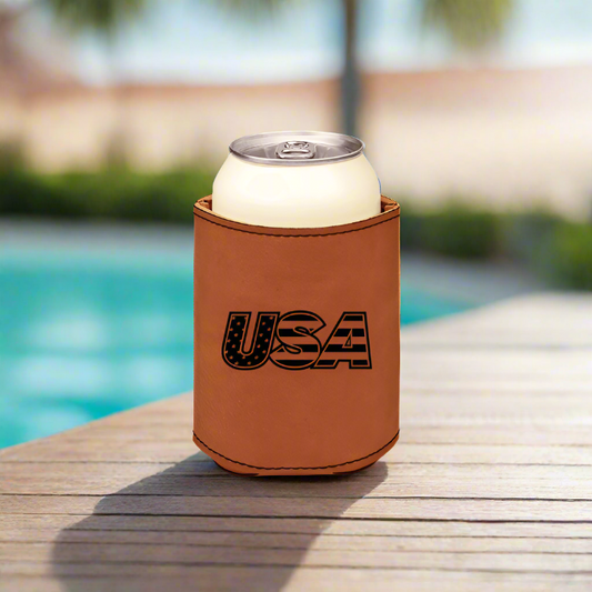 An brown leatherette can beverage holder with the text 'USA' on it, designed to hold a standard can, placed on a wooden surface with a pool in the background.