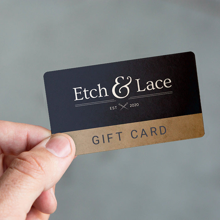 A hand holding a navy gift card with 'Etch & Lace' logo and 'GIFT CARD' text.