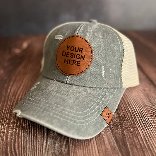 A gray personalized ponytail hat with a vegan leather patch that reads 'YOUR DESIGN HERE', featuring a ponytail back and a pre-curved brim.
