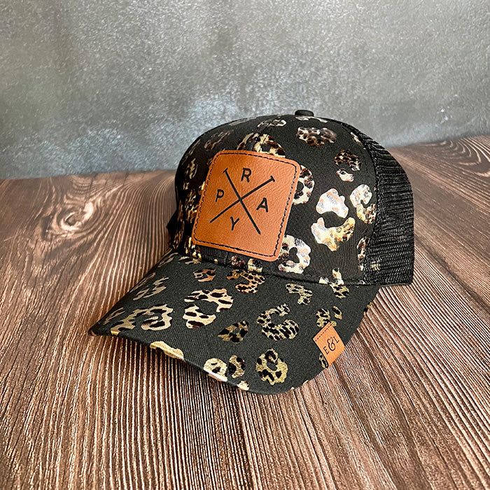 A black ponytail hat with a leopard animal print pattern and a brown 'PRAY' brand patch on the front.
