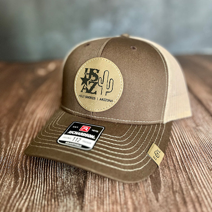 A brown trucker hat with 'Holy Smokes Club - Arizona' logo in tan leather on the front.