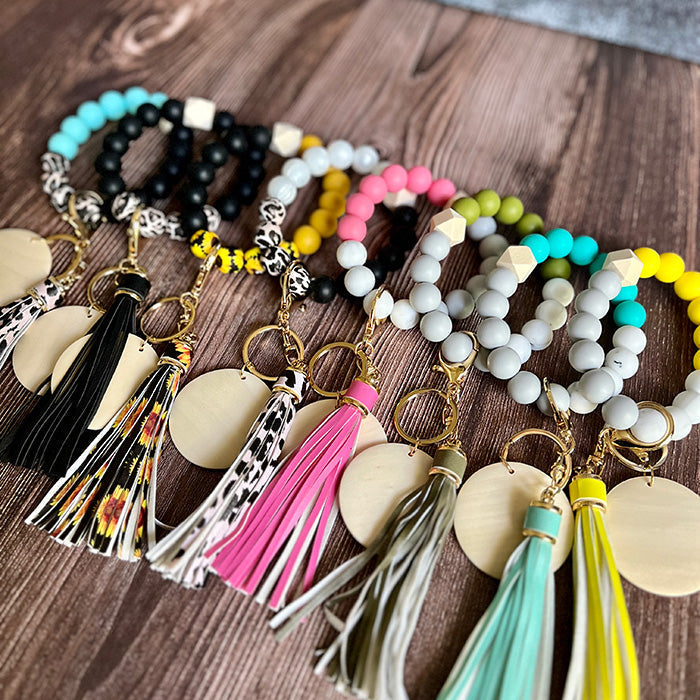 A collection of silicone bead wristlet keychains in various colors, featuring animal print and solid patterns, with tassel details.