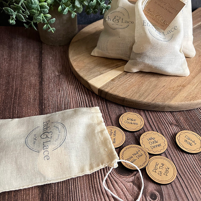 A set of wooden reward tokens with various engravings, scattered on a table alongside a hand-stamped muslin storage bag.