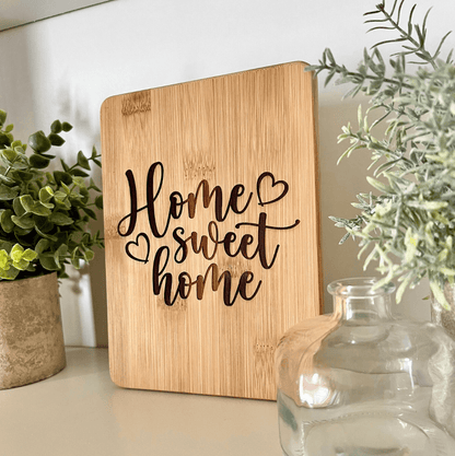 A bamboo charcuterie serving board with 'Home Sweet Home' text etched on it, placed on a kitchen counter.
